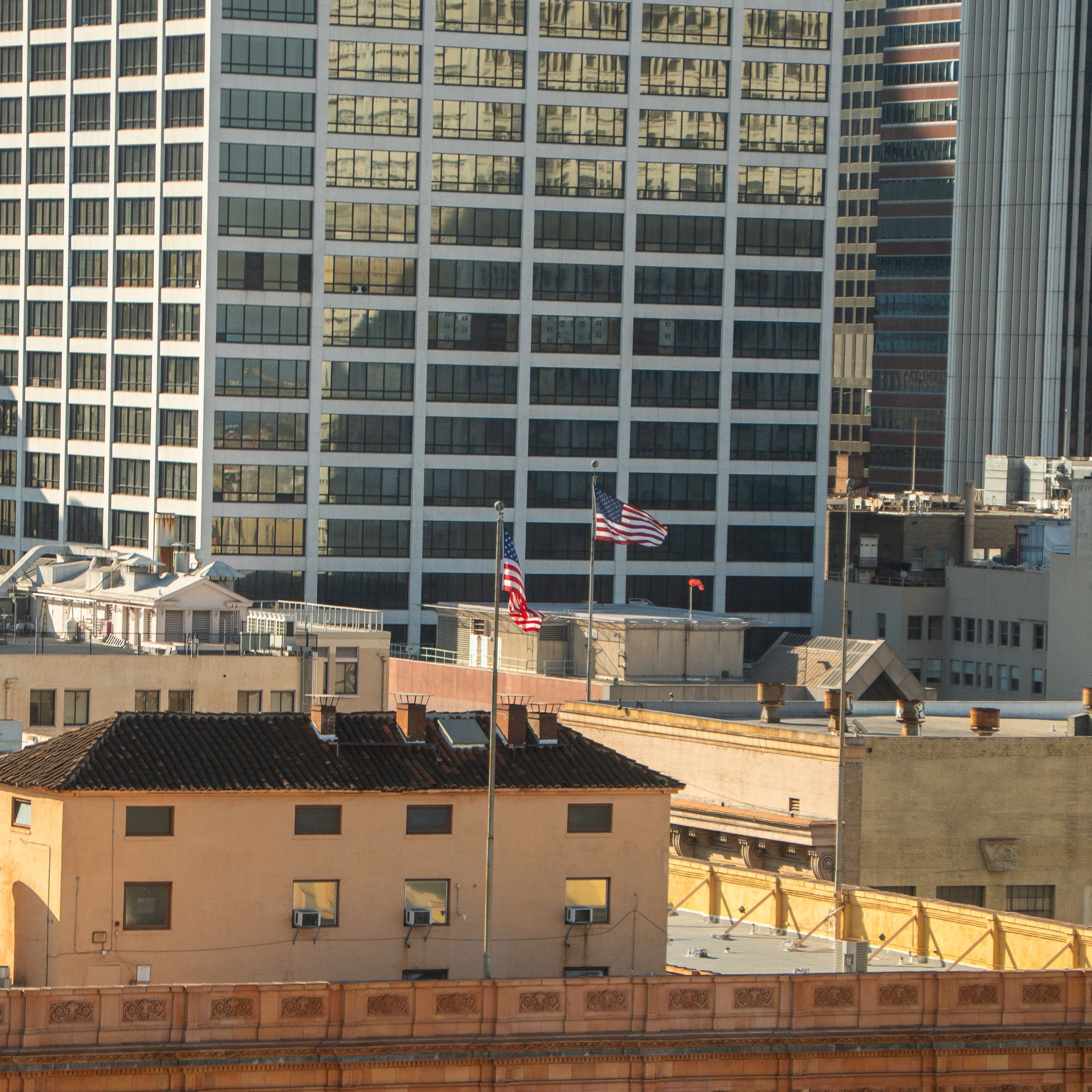 American flag on a rooftop in front of downtown skyscrapers